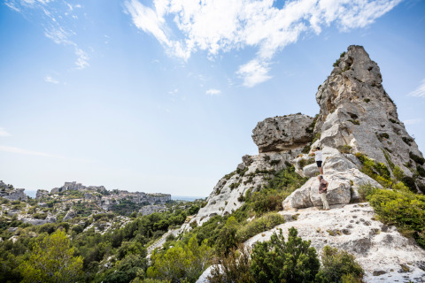 Deux personnes escaladent des rochers calcaires près de Fontvieille en Provence, France, sous un ciel bleu.