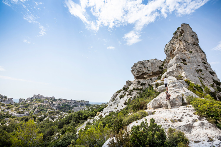 Deux personnes escaladent des rochers calcaires près de Fontvieille en Provence, France, sous un ciel bleu.