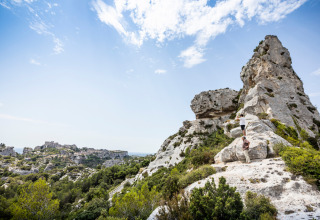 Twee mensen klimmen op kalkstenen rotsen bij Fontvieille in de Provence, Frankrijk, onder een blauwe lucht.