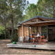 Familia sentada en la terraza de una cabaña de madera en Chalet Evasion, rodeada de naturaleza y pinos.