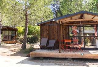 Twee houten lodges met terrassen en buitenmeubilair bij Chalet Evasion, Huttopia Fontvieille in Frankrijk.
