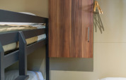 Foto del interior de un alojamiento glamping Chalet Evasion, con literas, cama individual y armario en la pared.
