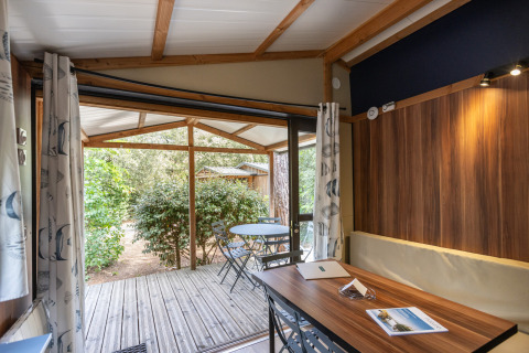 Binnenaanzicht van Chalet Evasion glamping met tafel, stoelen en overdekt terras tussen het groen.