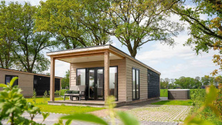 Panorama Wellness Lodge med jacuzzi og sauna, moderne hytte i naturskønne omgivelser med grønne træer.