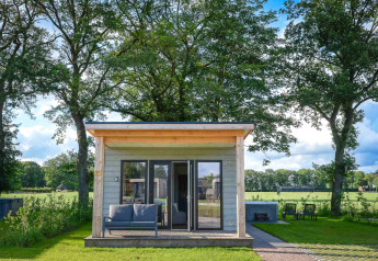 Panorama Wellness Lodge met jacuzzi en sauna op Vakantiepark Hölte, omgeven door weelderig groen.