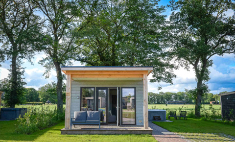 Panorama Wellness Lodge con jacuzzi e sauna al Vakantiepark Hölte, circondata da verde lussureggiante.