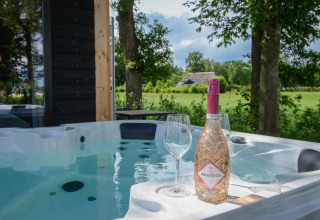 Bubbelbad buiten met prosecco en glazen bij Panorama Wellness Lodge op Vakantiepark Hölte.