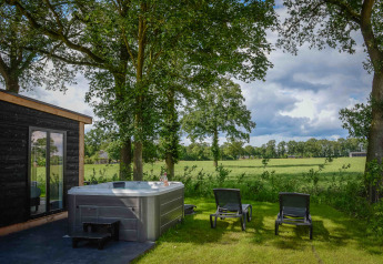 Außenbereich mit Whirlpool und Liegestühlen bei Panorama Wellness Lodge, Vakantiepark Hölte, Niederlande.