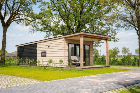 Gemütliche Wellness-Lodge mit Whirlpool und Sauna im Vakantiepark Hölte, Niederlande, in grüner Umgebung.