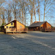 To træhytter i morgensol ved River Lodge, Camping de Koeksebelt, omringet af høje træer i Holland.