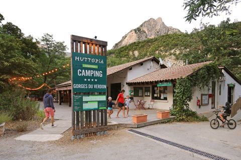 Entrée du parc de vacances Huttopia Gorges du Verdon avec visiteurs et paysages montagneux en arrière-plan.