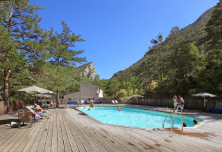Udendørs swimmingpool omgivet af træterrasse og bjerge på Huttopia Gorges du Verdon i Hauts-de-France.