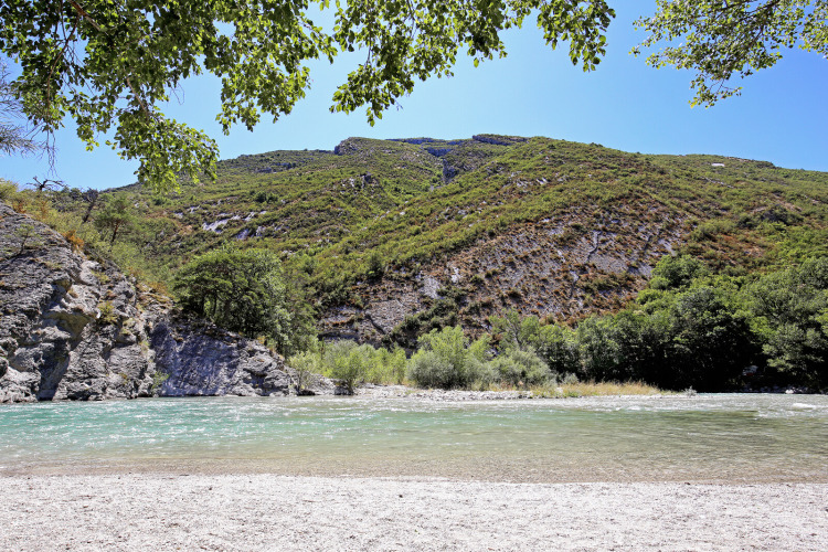 River with clear water, green hills, and blue sky at Huttopia Gorges du Verdon in Hauts-de-France, France.