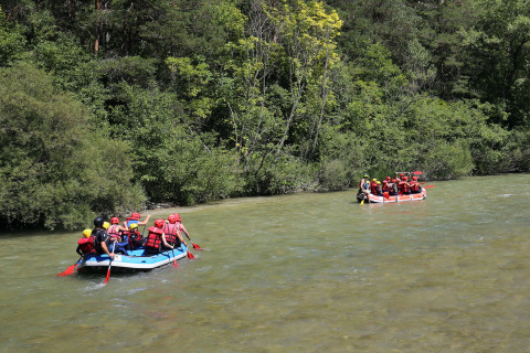 Personas con chalecos salvavidas y cascos hacen rafting en un río en Huttopia Gorges du Verdon, Francia.
