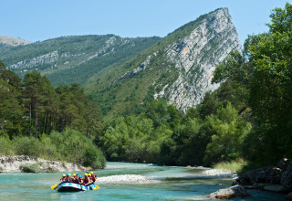 Persone fanno rafting su un fiume turchese tra alberi e montagne a Huttopia Gorges du Verdon, Francia.
