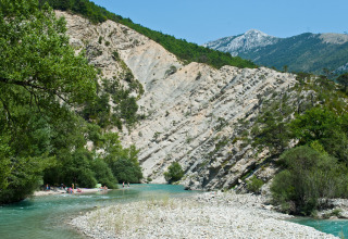 Folk slapper af ved en flod omgivet af grøn skov og dramatiske skrå klippeformationer i Gorges du Verdon.