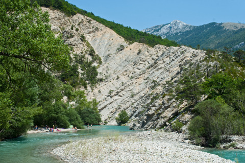 Persone si rilassano lungo un fiume turchese tra boschi verdi e suggestive scogliere delle Gorges du Verdon.