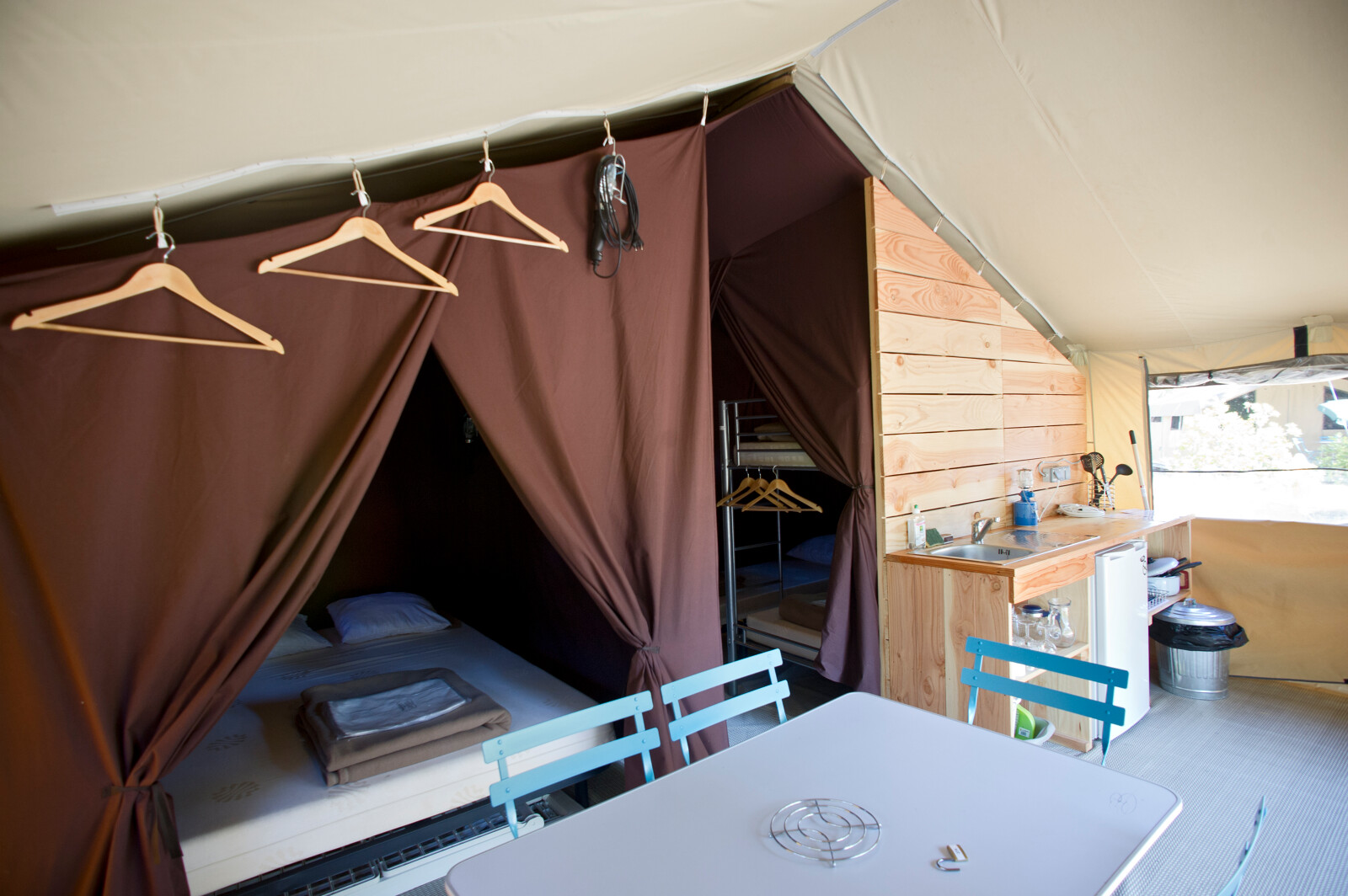 Interieur van een Toile&Bois tent Sweet safaritent met bed, kitchenette en eettafel.