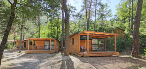 Cabañas de madera con terrazas entre árboles en Chalet Evasion, Huttopia Gorges du Verdon, Francia.