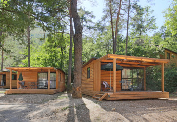 Houten chalets met terras te midden van bomen bij Chalet Evasion, Huttopia Gorges du Verdon, Frankrijk.