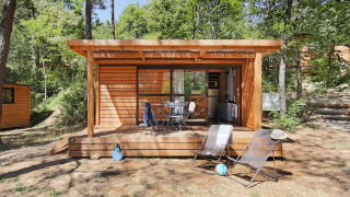 Chalet Evasion houten huisje met terras en ligstoelen, omringd door een rustige bosrijke omgeving.