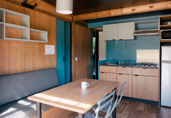 Indvendigt billede af Chalet Evasion glamping indkvartering med køkken, sofa, bord og stole.