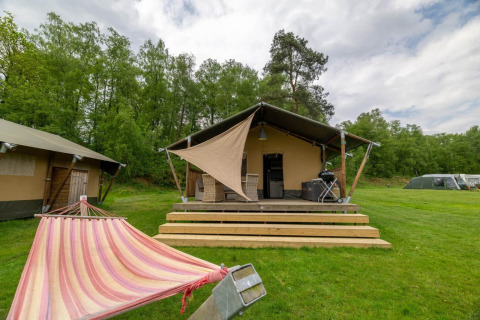 Tienda safari en Wilsumer Berge, Alemania, con hamaca, terraza de madera y barbacoa en entorno verde.