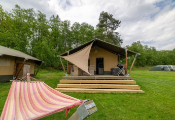 Tienda safari en Wilsumer Berge, Alemania, con hamaca, terraza de madera y barbacoa en entorno verde.