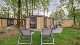 Photo extérieure du lodge Module Wood Hottub avec chaises longues et salon de jardin dans une forêt.