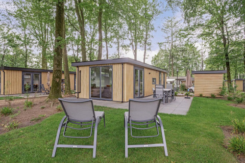 Modernes Ferienhaus namens Module Wood Hottub, mit Liegestühlen und Terrasse in einem bewaldeten Gebiet.