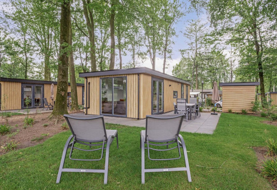 Udendørsbillede af en moderne lodge ved navn Module Wood Hottub med liggestole og terrasse i skoven.