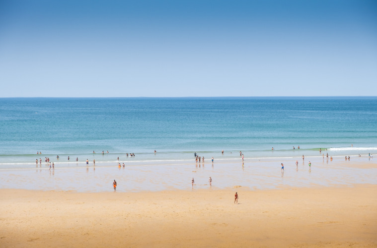 Menschen entspannen am Sandstrand von Huttopia Lac de Carcans in Nouvelle-Aquitaine, Frankreich.