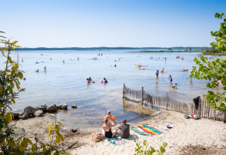 Families relax on the beach and swim in the lake at Huttopia Lac de Carcans in Nouvelle-Aquitaine, France.