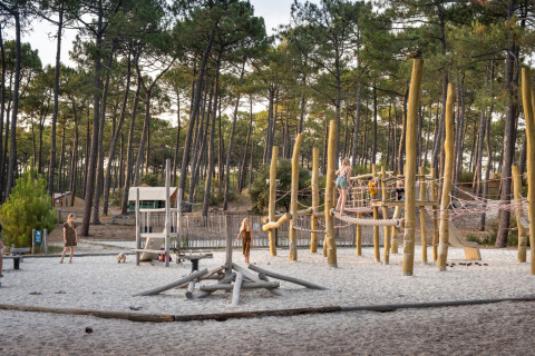 Niños juegan en un área de juegos de madera en el bosque en Huttopia Lac de Carcans, Nouvelle-Aquitaine, Francia.