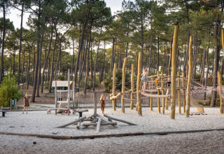 Børn leger på en legeplads i en skov ved Huttopia Lac de Carcans feriested i Nouvelle-Aquitaine, Frankrig.