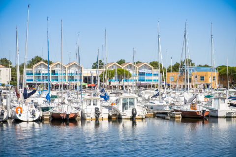 View of boats docked at the marina in Huttopia Lac de Carcans holiday park, Nouvelle-Aquitaine, France, on a sunny day.