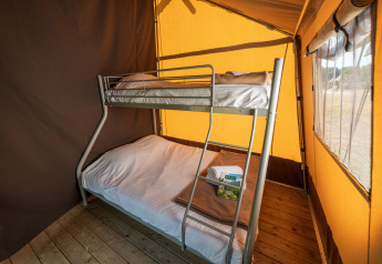 Interieur van een safaritent met een stapelbed en houten vloer, perfect voor een comfortabele kampeerervaring.