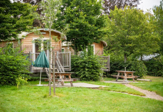 Træhytter omgivet af grønne træer og picnicborde ved Huttopia Etang de Fouché, Bourgogne, Frankrig.