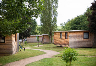 Houten huisjes tussen het groen op vakantiepark Huttopia Etang de Fouché in Bourgogne, Frankrijk, met paadjes.