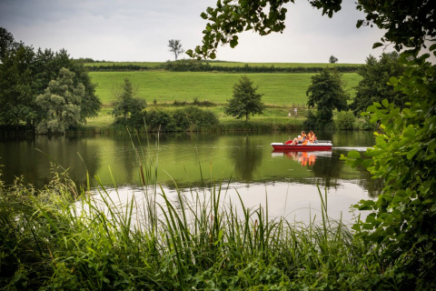Famiglia in pedalò su un lago tranquillo circondato dal verde a Huttopia Etang de Fouché, Borgogna, Francia.
