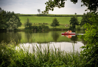 Familia paseando en bote de pedales por un lago rodeado de naturaleza en Huttopia Etang de Fouché, Borgoña, Francia.