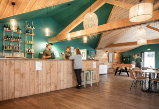 Grand salon en bois avec bar, espace jeux et ambiance chaleureuse à Huttopia Etang de Fouché, Bourgogne.