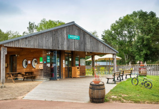 Entrance to Huttopia Etang de Fouché holiday park in Bourgogne-Franche-Comté, France, with benches and bike.