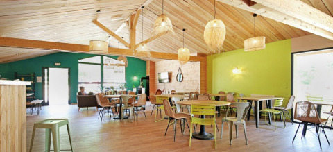 Salón comedor moderno y luminoso con techo de madera en Huttopia Etang de Fouché, parque vacacional en Borgoña.