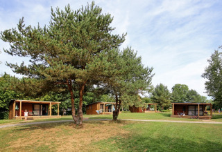 Cabanes en bois au parc de vacances Huttopia Etang de Fouché entourées d’arbres et de pelouse, Bourgogne, France.