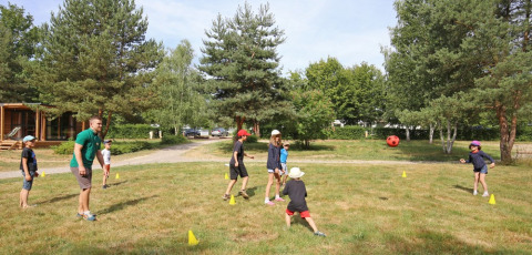 Niños y un adulto juegan a la pelota al aire libre en el parque vacacional Huttopia Etang de Fouché en Borgoña, Francia.
