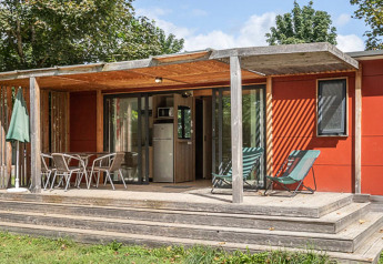 Casa móvil Vancouver en Huttopia Etang de Fouché, Francia, con terraza de madera y muebles de exterior rodeada de verde.