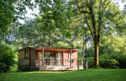 Mobil-home Vancouver avec terrasse en bois, entouré d'arbres et de verdure par une journée ensoleillée.