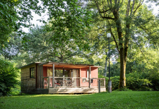 Casa móvil Vancouver con terraza de madera, rodeada de césped y árboles bajo la luz del sol.