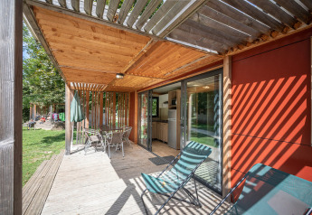 Træterrasse med solstriber, havestole og spisebord udenfor Mobile home Vancouver med udsigt til grønt område.